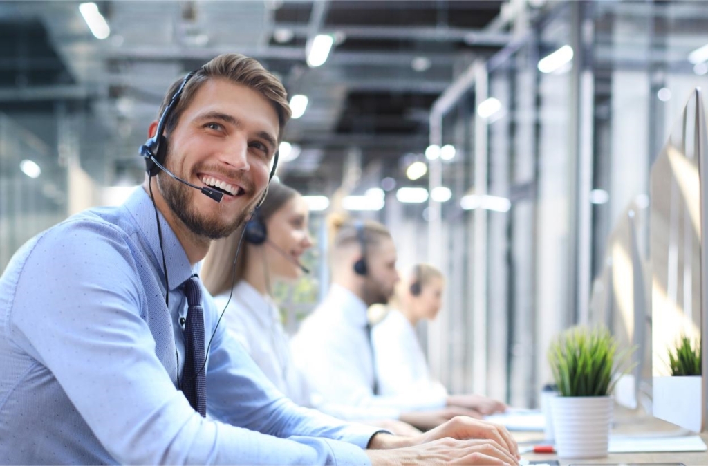 Porträt Call-Center-Mitarbeiter in Begleitung-von seinem Team -lächelnder Kundensupport-Mitarbeiter.